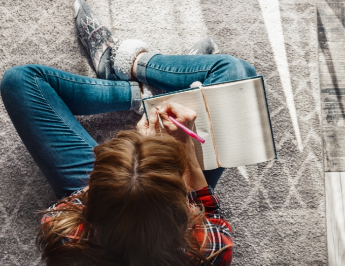 Lady sits on the floor writing 